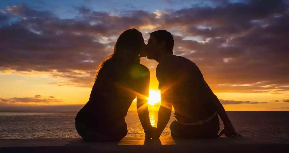 Two persons kissing each other in the sunset