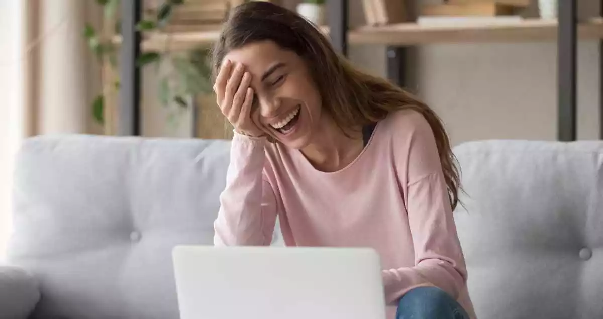 A woman laughing in front of a computer