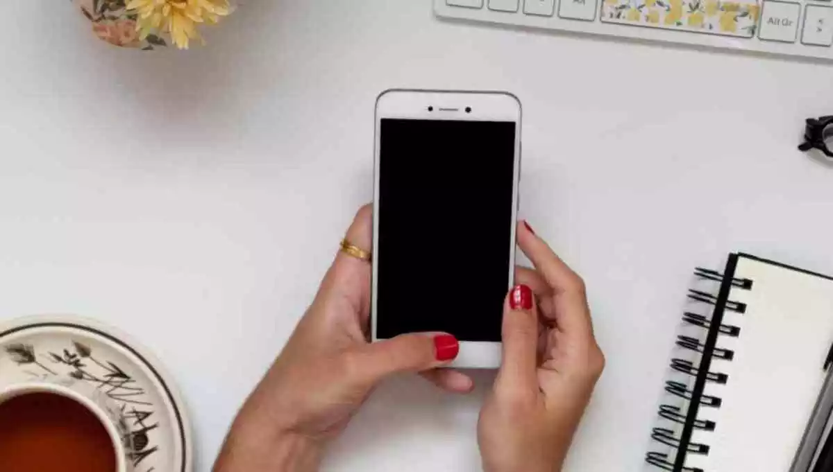 Girl hands holding a smartphone, perfect for mockup. Composition of home office, flat lay perspective