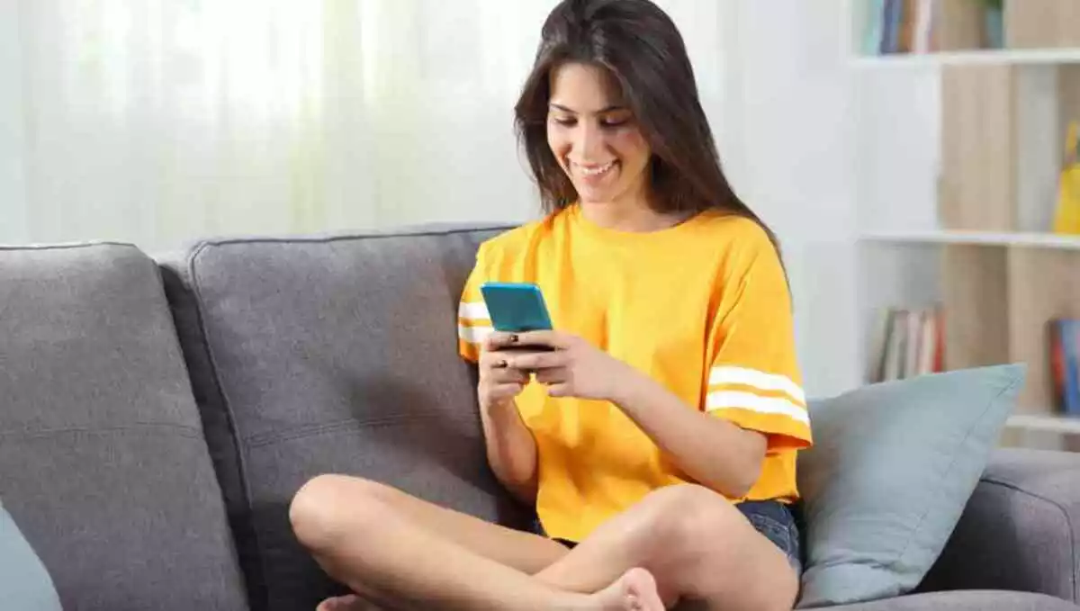 Happy teen in yellow using phone at home