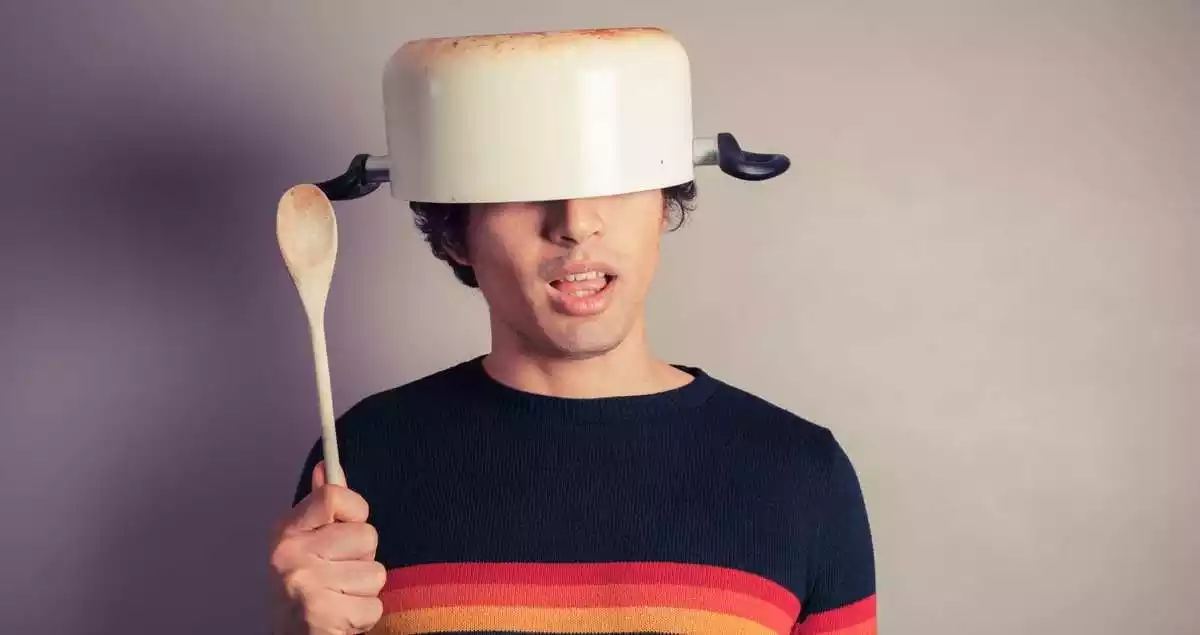 A man with a pan on his head, acting like a fool.